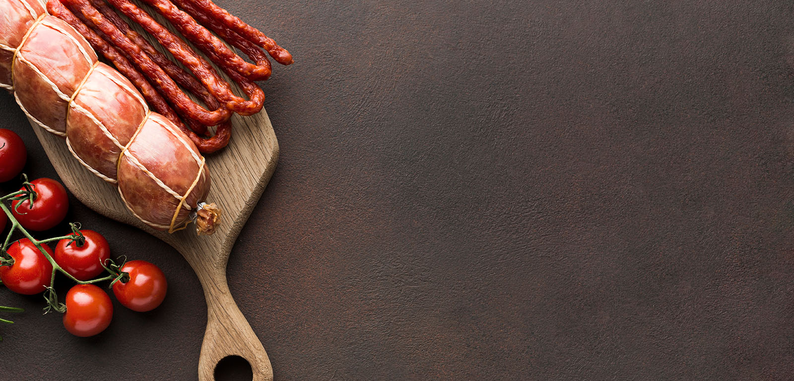 Zwei verschiedene Wurstsorten auf Holzbrett und Tomatenstaude
